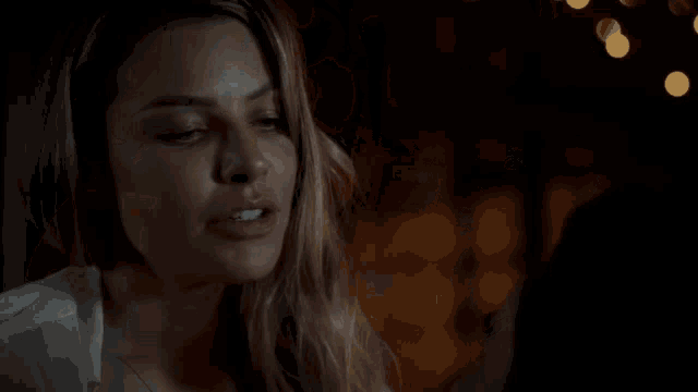 a woman is touching a shirtless man 's face in a dark room
