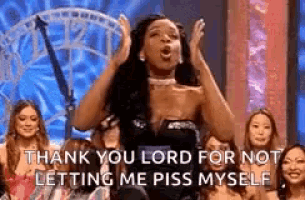 a woman is standing on a stage with her hands in the air and screaming .