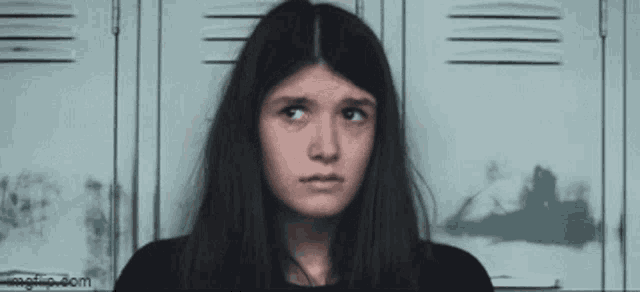 a girl is standing in front of a row of lockers with a picture of a boat on the wall behind her