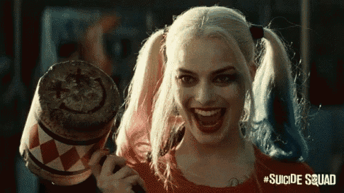 harley quinn from suicide squad is smiling while holding a hammer .