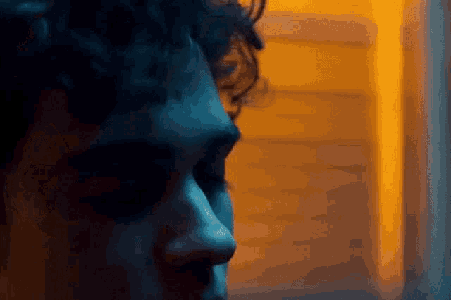 a close up of a man 's face in a dark room with a yellow background .