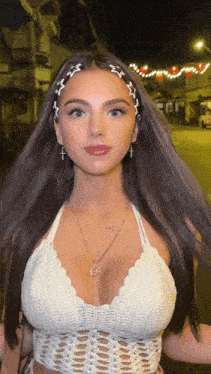 a woman wearing a white crocheted top with a cross on her head