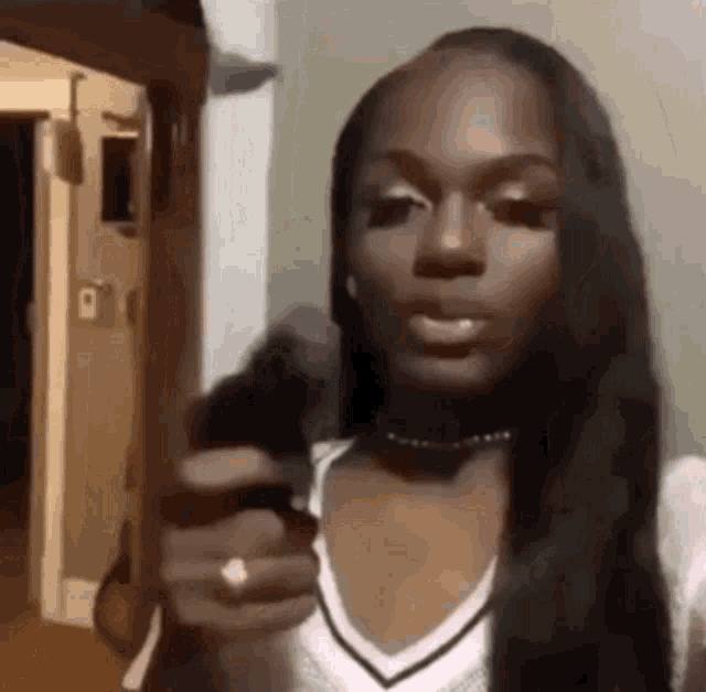 a woman with long hair is pointing at the camera while wearing a white shirt .