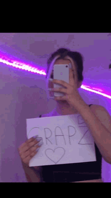 a girl taking a picture of herself with a sign that says grapz