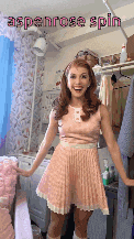 a woman in a pink dress is standing in a laundry room and smiling .