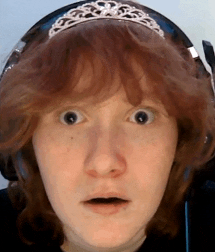 a woman wearing headphones and a tiara makes a surprised face