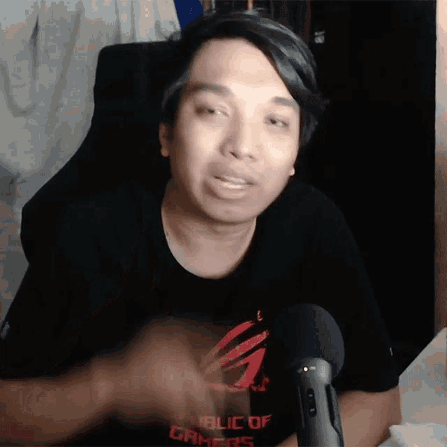 a man wearing a republic of gamers t-shirt talking into a microphone