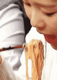 a close up of a person eating noodles with chopsticks