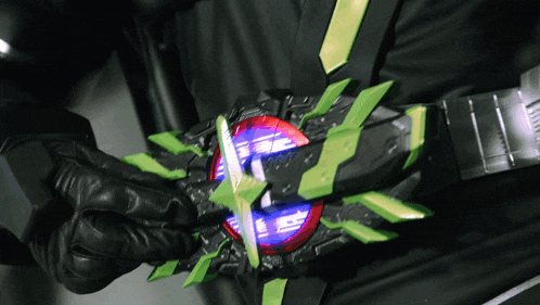 a person wearing a black glove is holding a green and red object with the letter e on it