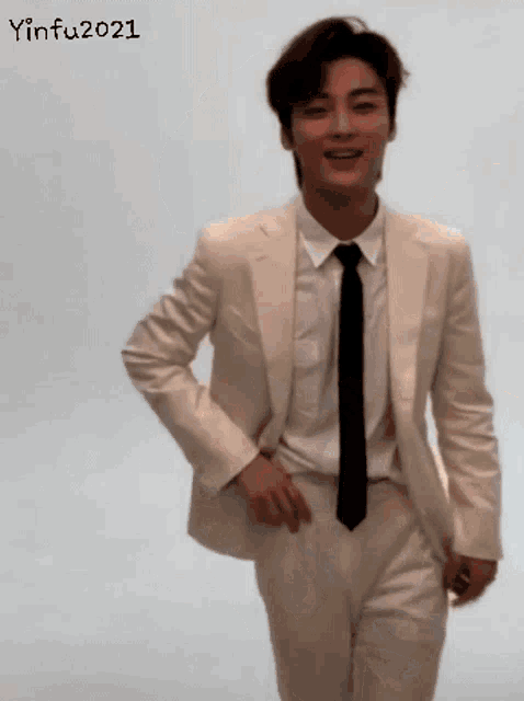 a young man in a white suit and tie is smiling