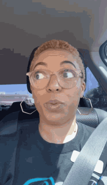 a woman wearing glasses and a black shirt is sitting in the back seat of a car