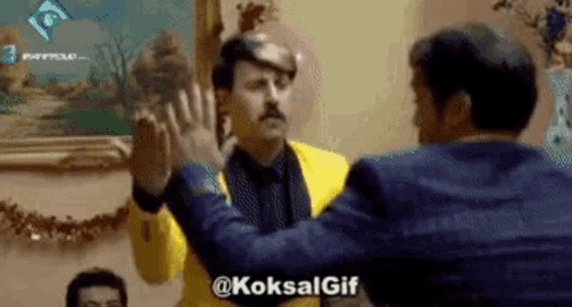 two men are giving each other a high five in front of a painting .