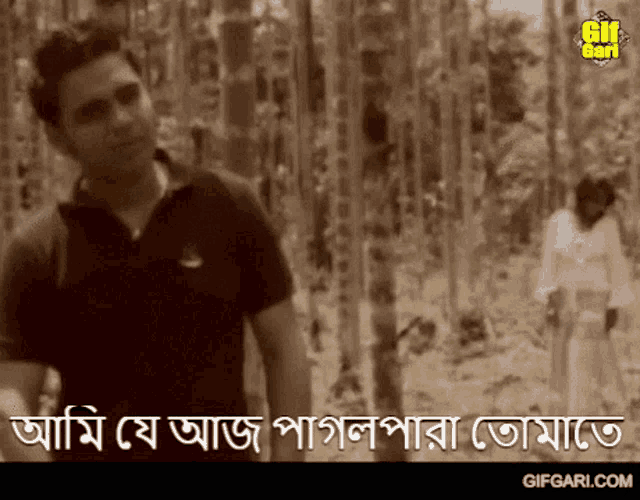 a man in a black shirt is standing in a forest with a gifgari.com logo on the bottom