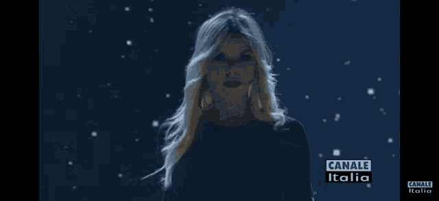 a woman stands in front of a blue background with canale italia written on it