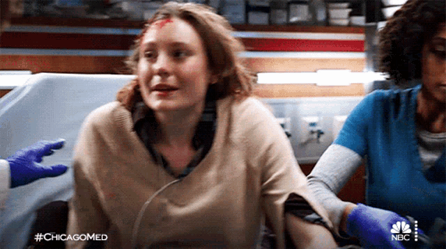 a woman with a bandage on her forehead is being helped by a nurse from nbc