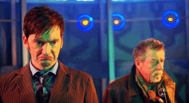 a man in a suit and tie is making a funny face while standing next to another man