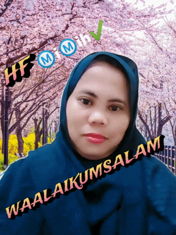 a woman wearing a blue hijab says waalaikumsalam in front of cherry blossoms