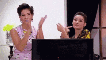 two women are clapping in front of a lenovo monitor