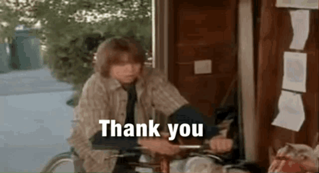 a young man is riding a bicycle in a doorway and saying `` thank you '' .
