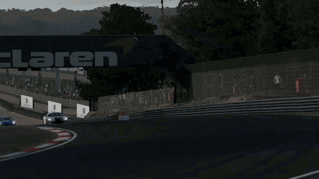 a group of sports cars are driving on a track under a mclaren sign