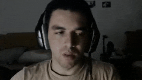 a man wearing headphones looks at the camera in the dark
