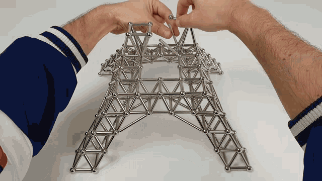 a person in a blue and white jacket is playing with a toy that looks like an eiffel tower
