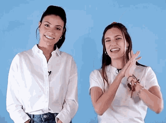 two women wearing white shirts are standing next to each other and smiling .