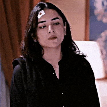 a woman with a bandage on her forehead looks serious