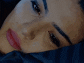 a close up of a woman 's face laying on a bed with her eyes closed .
