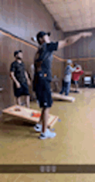 a man is throwing a frisbee in the air while standing on a cornhole board .
