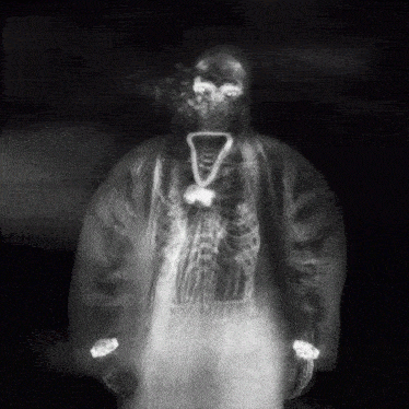 a black and white photo of a person with a necklace around their neck with the letter v on it