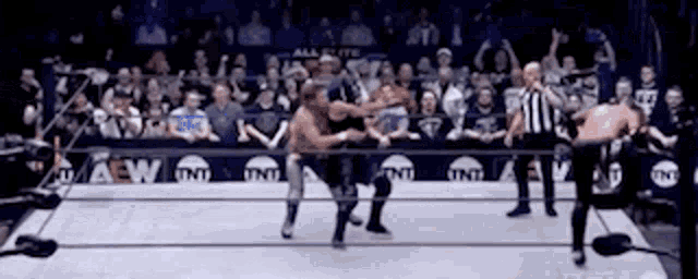 a group of wrestlers are fighting in a ring with a referee watching .