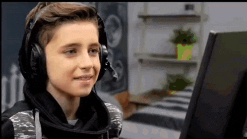 a young boy is wearing headphones and looking at a computer screen .