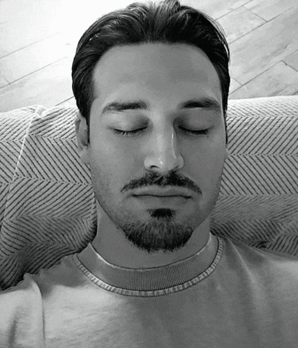 a man with his eyes closed is wearing a sweater