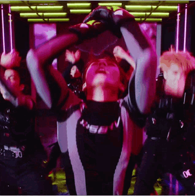 a group of people are dancing in a dark room with purple lights