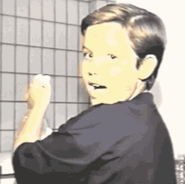 a young boy in a black shirt is looking at the camera