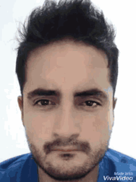 a close up of a man 's face with a beard and a blue shirt .