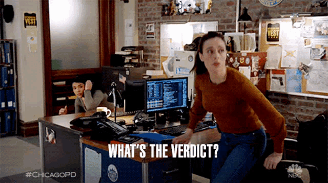 a woman standing in front of a desk with the words what 's the verdict