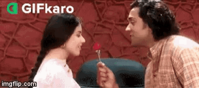 a man is giving a woman a rose on a stick and they are looking at each other .