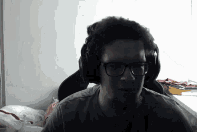 a man wearing glasses and headphones is sitting in a dark room