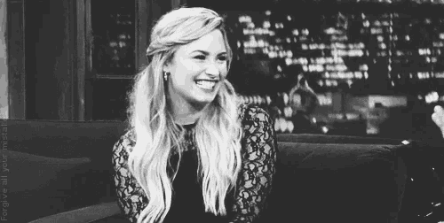 a black and white photo of a woman laughing on a couch .