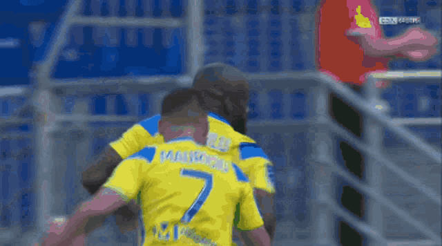 two soccer players wearing yellow jerseys with the number 7 on the back