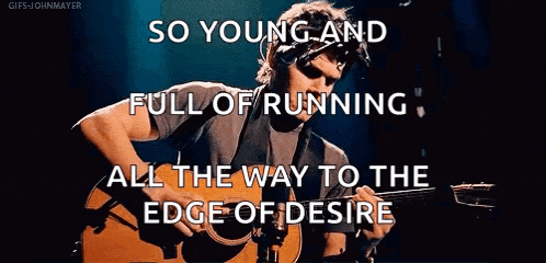 a man is playing a guitar on a stage while singing .