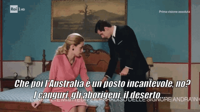 a man in a suit stands next to a woman on a bed with the words che poi l' australia e un posto incantevole