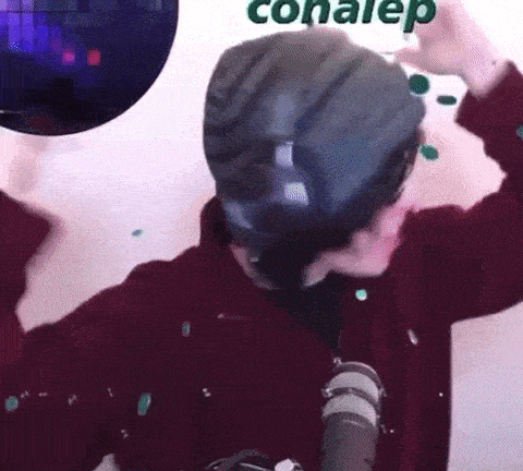 a man wearing a hat is standing in front of a microphone and a disco ball .