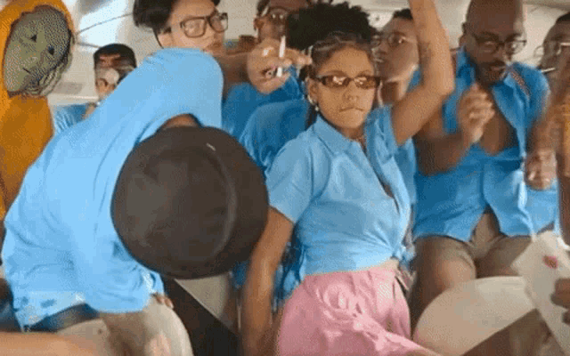 a group of people in blue shirts and pink skirts are dancing on a plane