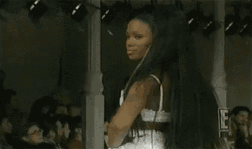 a woman in a white bra and skirt is walking down a runway .