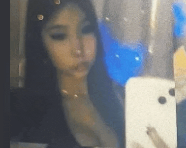 a woman is taking a selfie with her cell phone in front of a mirror .