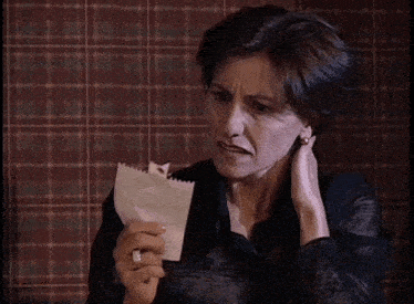 a woman is holding a piece of paper with a ring on her finger