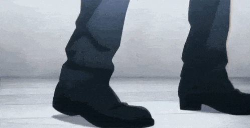 a close up of a person 's feet in black boots walking on a white floor .